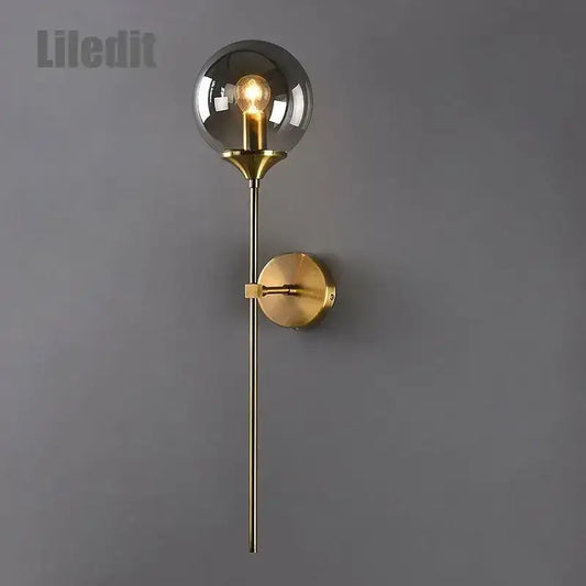 Modern golden glass ball wall lamp with a gold-toned stem and spherical smoked glass globe decorbites golden glass sconce