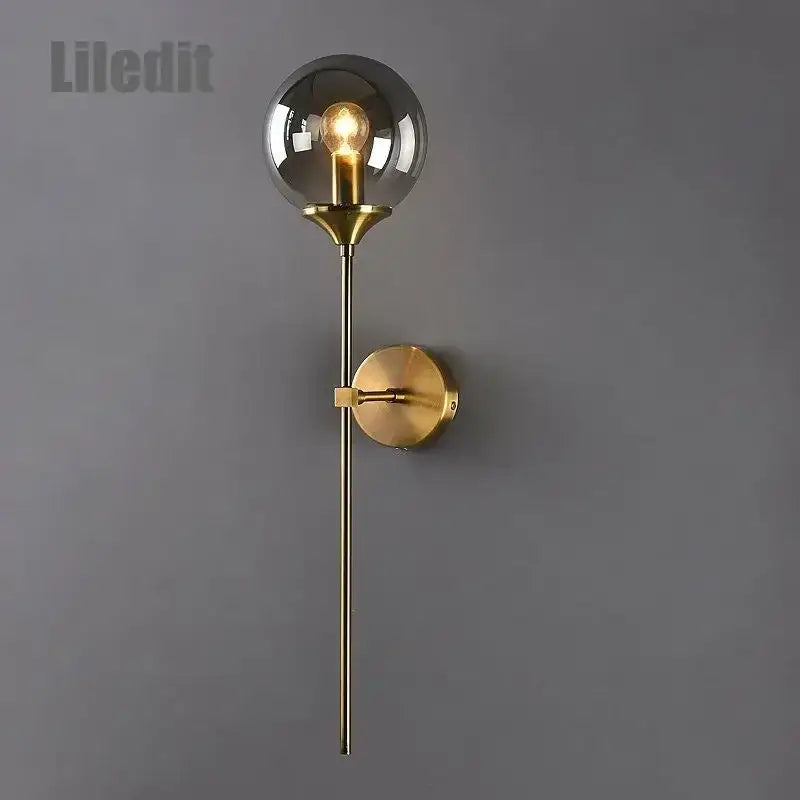 Modern golden glass ball wall lamp with a gold-toned stem and spherical smoked glass globe decorbites golden glass sconce