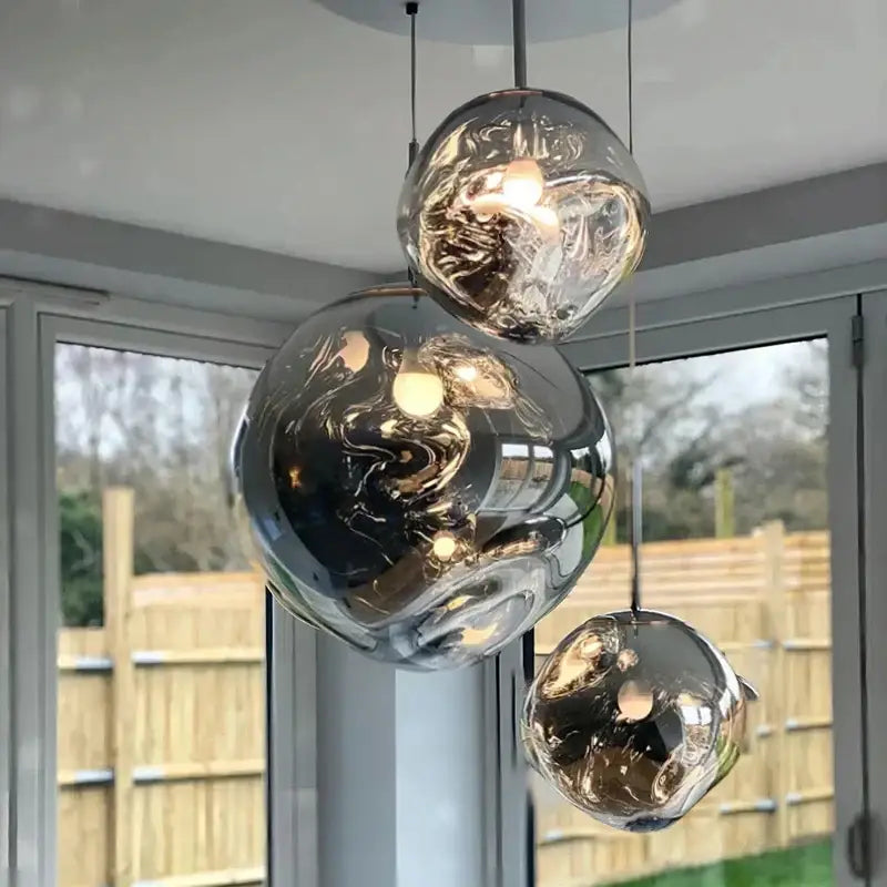 Set of three modern golden glass lava pendant lights with reflective metallic finish and warm illumination for dining room decorbites glass lava