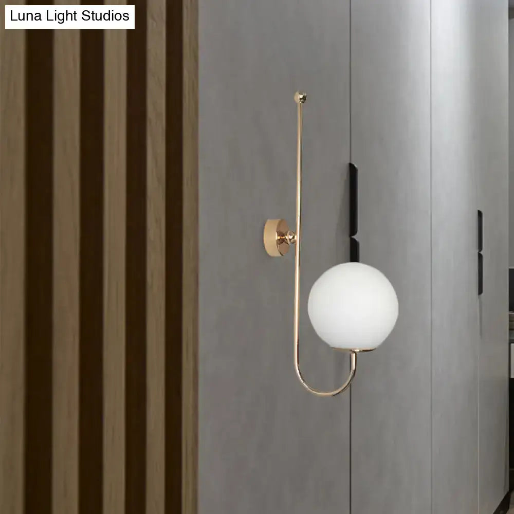 Modern golden gooseneck wall sconce with a frosted glass ball shade and a sleek curved arm for bedroom lighting
