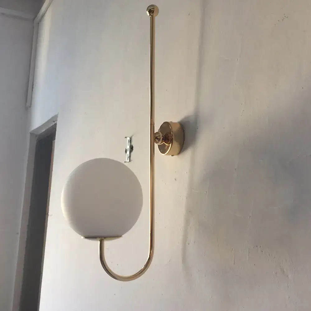 Modern golden gooseneck wall sconce with frosted glass ball shade and sleek curved metal arm for bedroom lighting