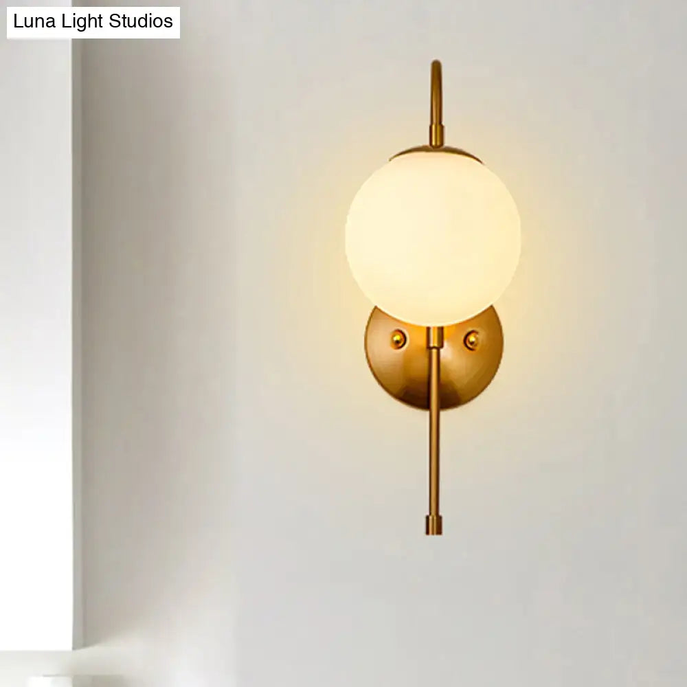 Modern golden gooseneck wall sconce with frosted glass ball shade and minimalist metal frame for bedroom lighting