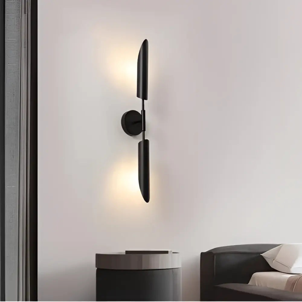 Black minimalist wall lamp with sleek vertical arms and circular base for decorbites golden inclined tube luxury spaces