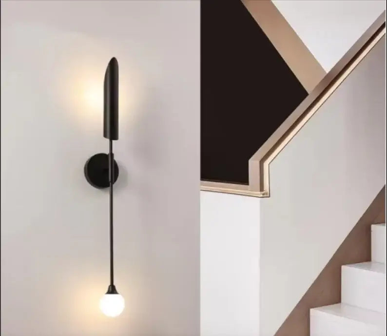 Modern black minimalist wall lamp with inclined tube design and warm-glowing spherical bulb for decorbites golden inclined use