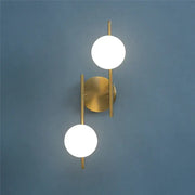 Modern gold-toned decorbites golden indoor wall sconce with two spherical frosted glass shades for bedroom use