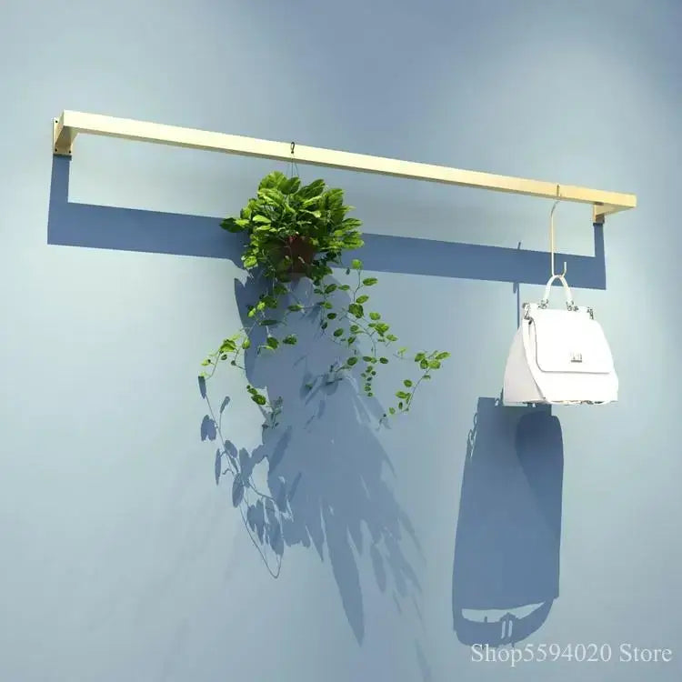 A modern golden iron ladder shelf with light wood finish holds a hanging green plant and white handbag for decorbites