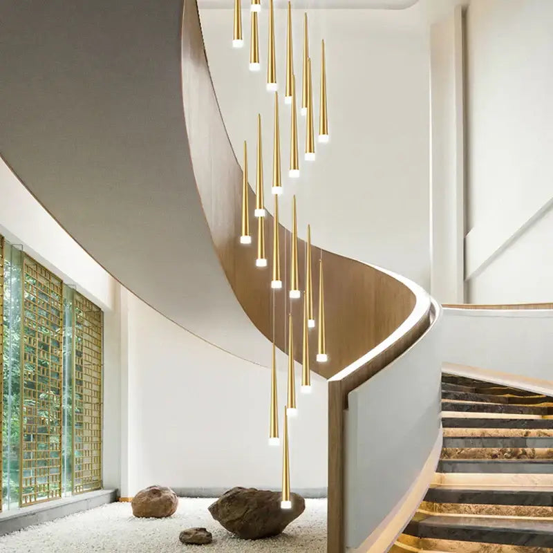 A modern decorbites golden led tapered chandelier with slender rods hangs above a curved staircase for living room lighting