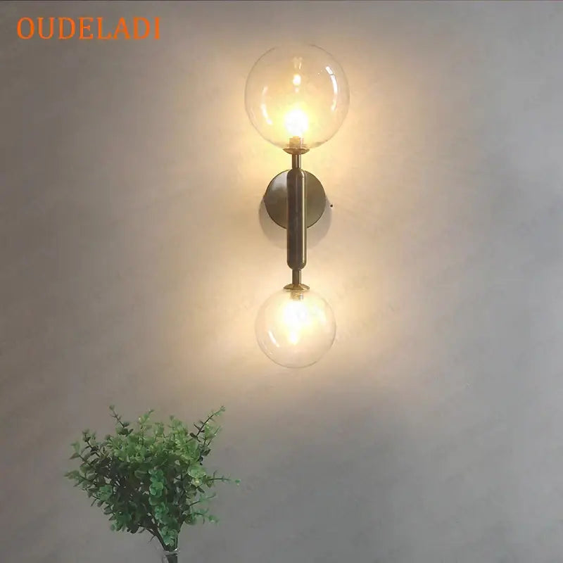 Oudeladi wall sconce with two clear glass globe bulbs and brushed brass finish in modern golden led wall decorbites golden led style