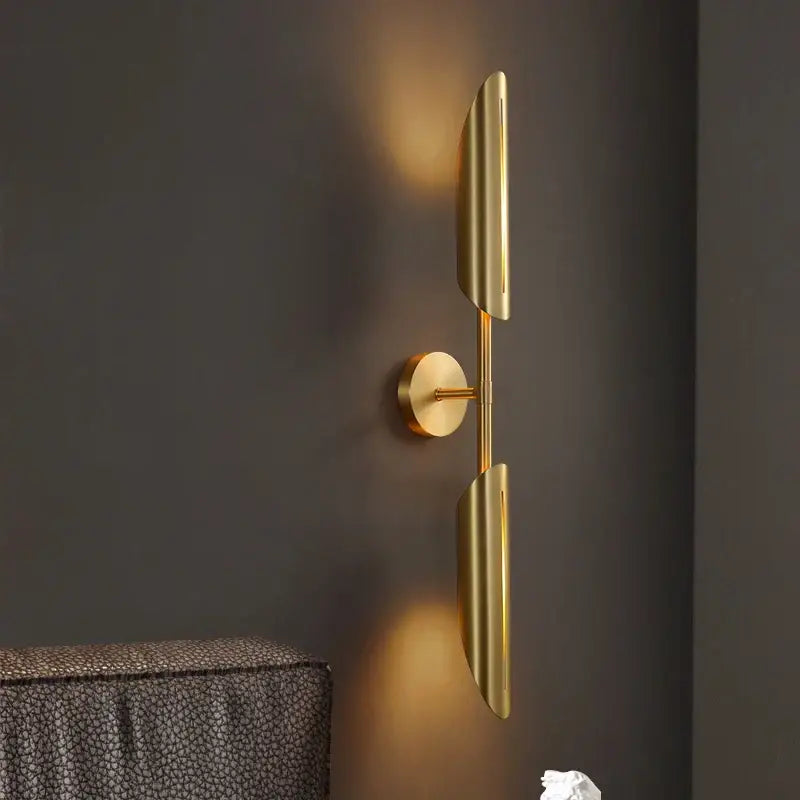 Modern golden metal led wall lamps with sleek elongated leaf-shaped shades and minimalist circular base for bedroom decorbites decor