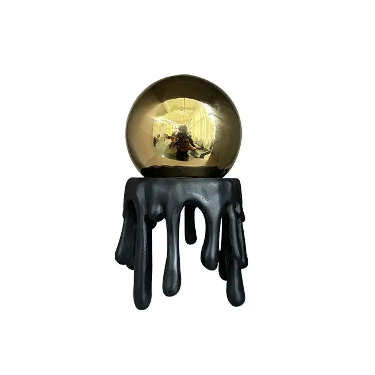 A sleek reflective gold sphere atop a black dripping resin base modern golden octopus spherical decorbites golden octopus decor