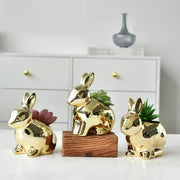 Modern golden ceramic flower pots shaped as reflective rabbit planters with small succulents for living room decor