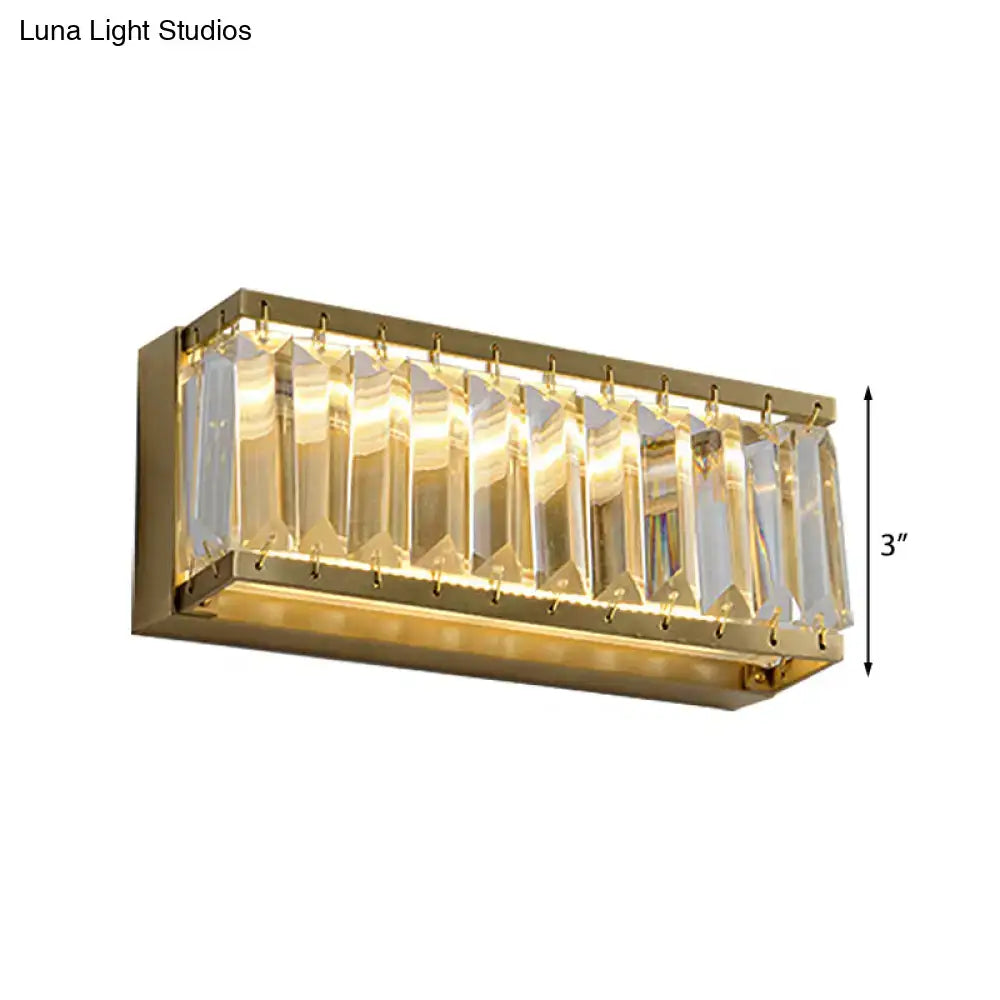 Modern golden rectangle led wall sconce with clear faceted crystal prisms refracting warm light and gold finish