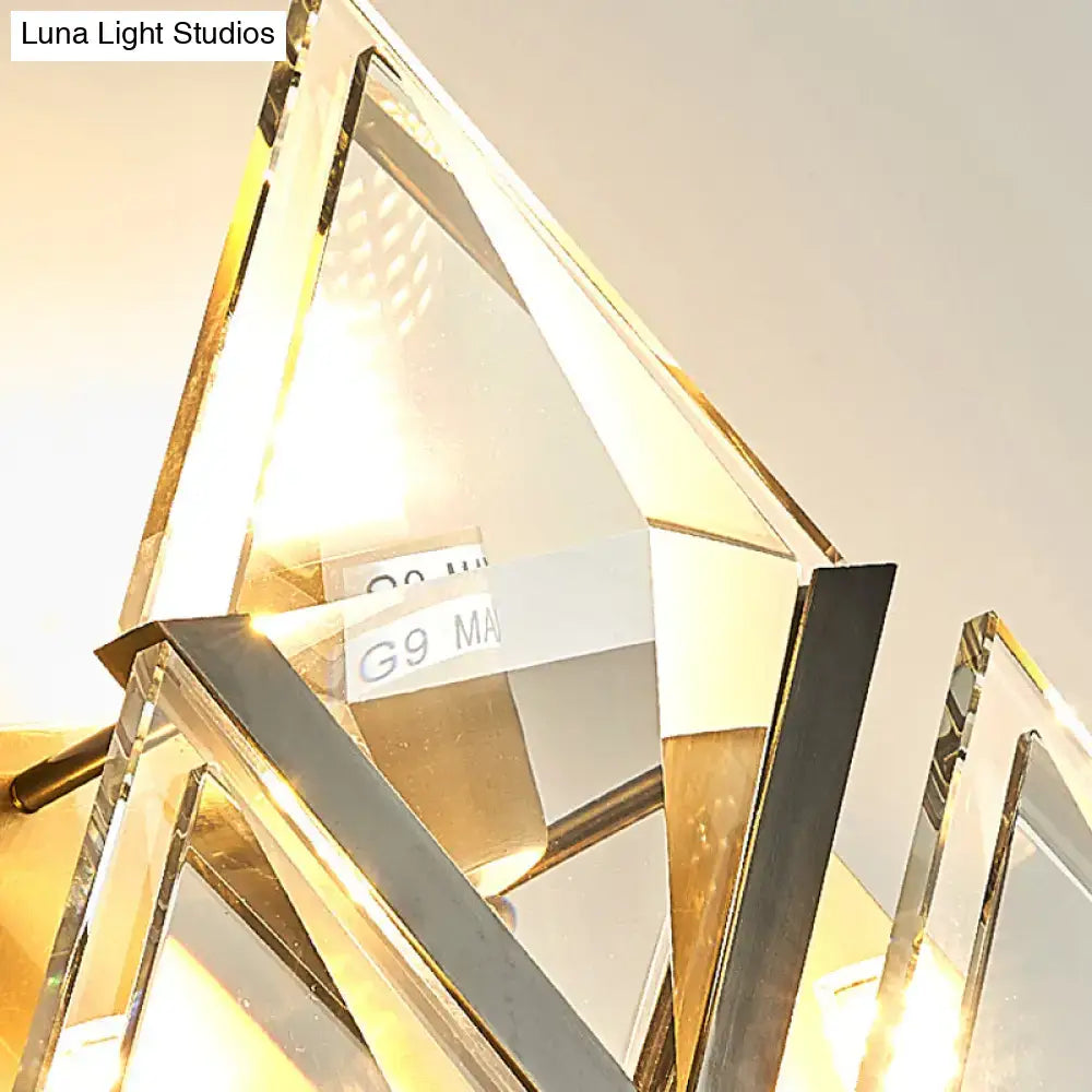 Modern style wall sconce light with clear crystal prisms and polished gold-toned metal for bedroom decor