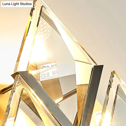 Modern style wall sconce light with clear crystal prisms and polished gold-toned metal for bedroom decor