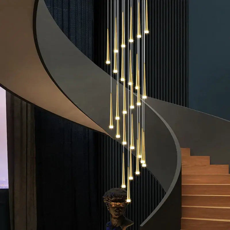 Modern golden tapered led chandelier with slender rods and warm lights suspended above spiral staircase decorbites golden tapered