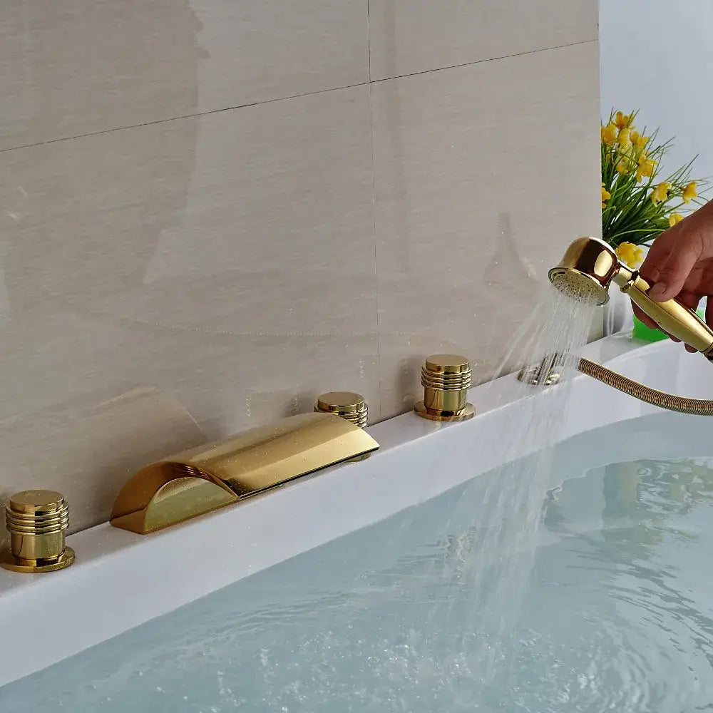 Modern golden widespread brass bathtub faucet with handheld shower featuring three cylindrical handles in sleek design