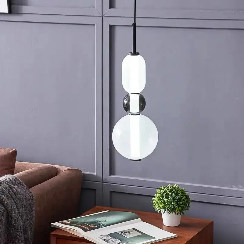 Modern gradient glass pendant light featuring a black stem and three stacked glass orbs for dining room use