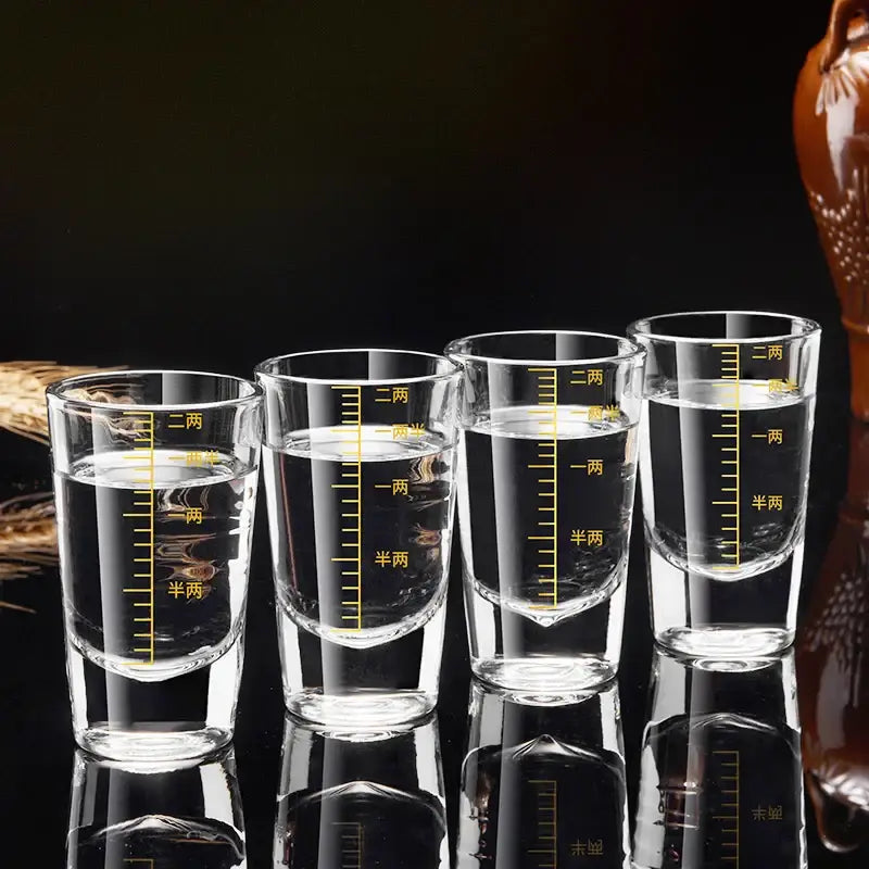 Four clear glass brandy cups with yellow chinese measurement markings in a modern graduated glass spirit set