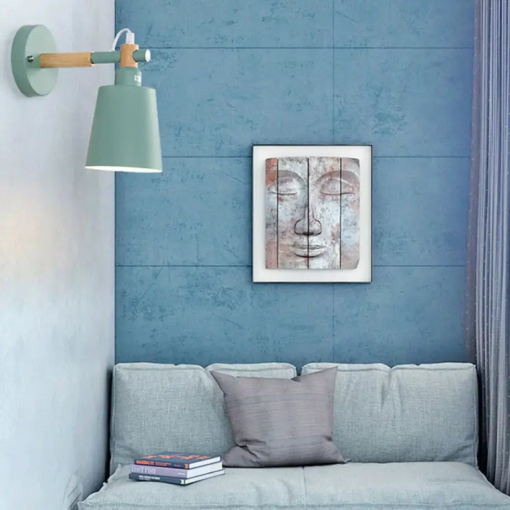 Modern gray and wood wall sconce light with matte sage green shade and wooden arm featuring white wiring for bedroom use