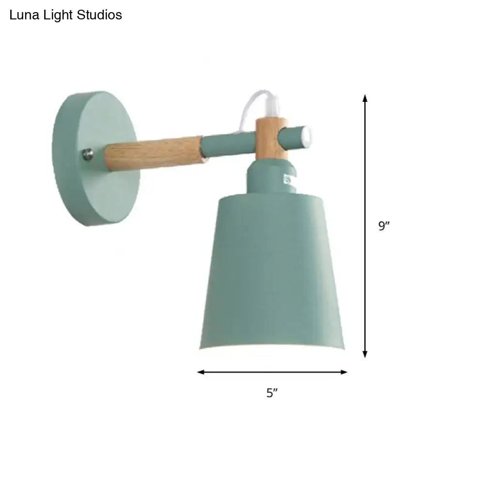 A mint green wall sconce light with a wooden arm and cylindrical shade in modern gray and wood design