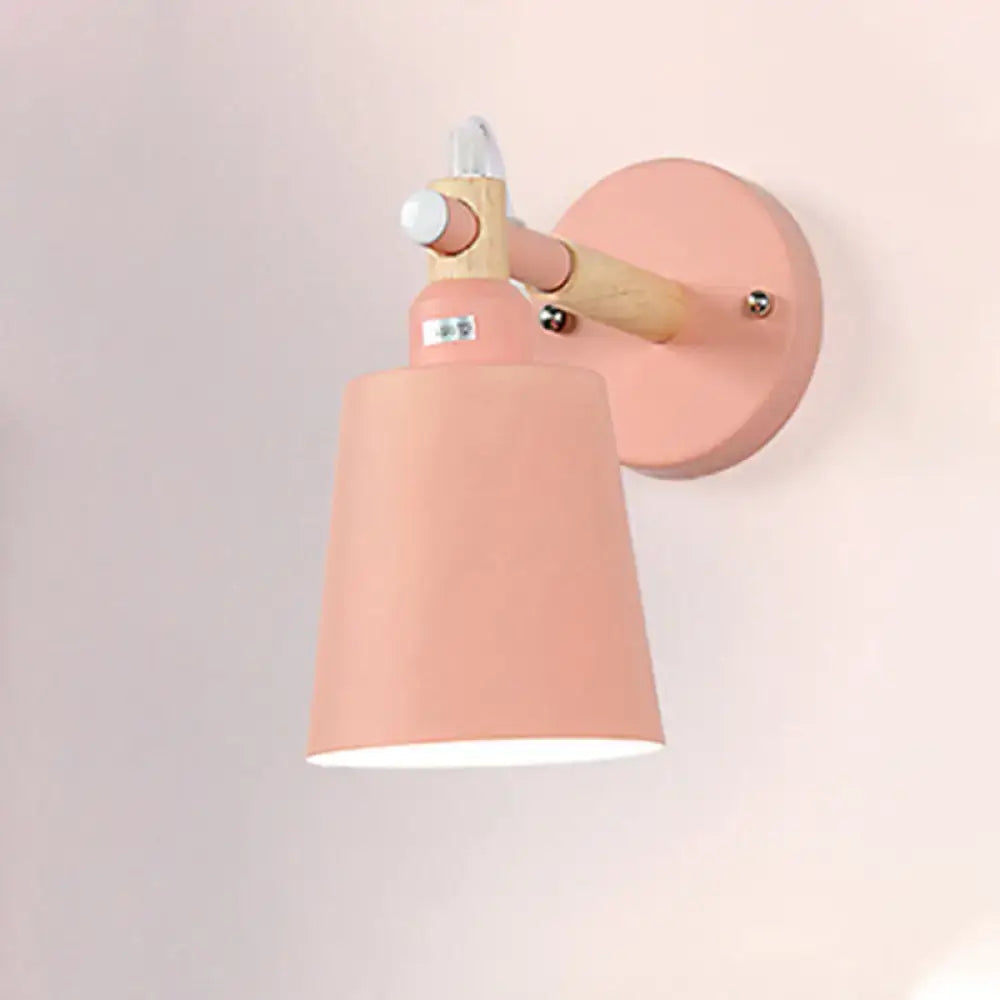 Modern gray and wood wall sconce light featuring a pastel pink metal shade with wooden arm and circular base for bedroom use