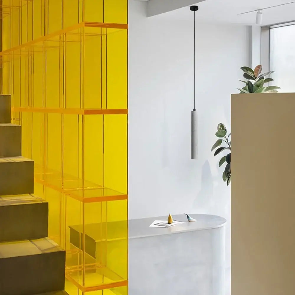 Vibrant yellow translucent acrylic shelving unit with geometric grid design paired with modern gray decorbites concrete tube pendant light triple chandelier
