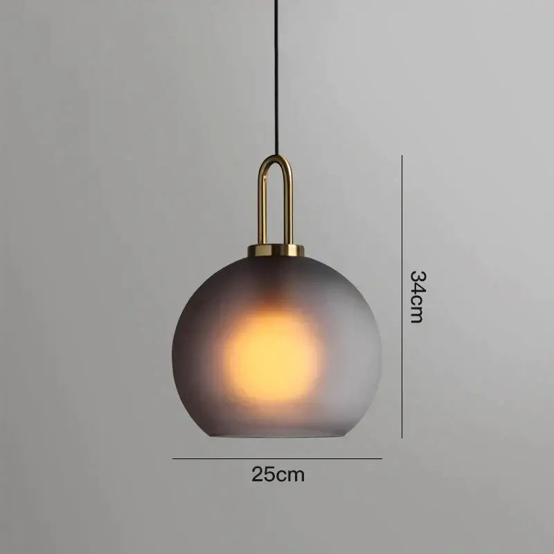 A sleek modern gray glass ball pendant light with frosted shade and brass accents ideal for dining room decorbites