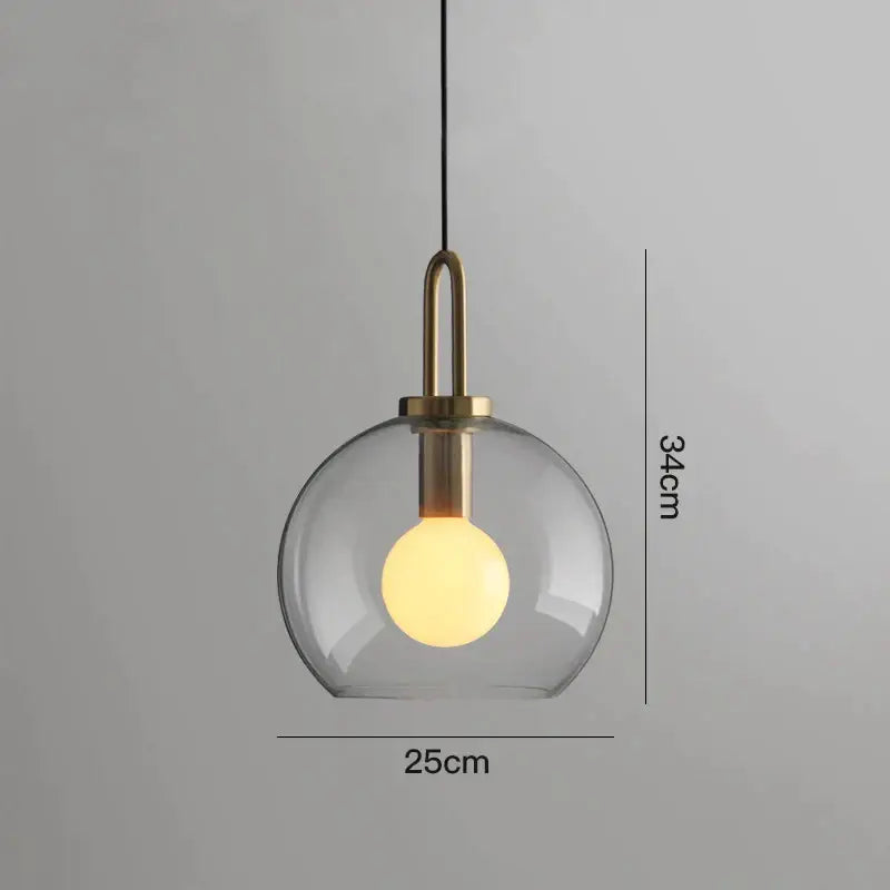 Modern gray glass ball pendant light with brass accents featuring a clear glass globe and warm-toned exposed bulb
