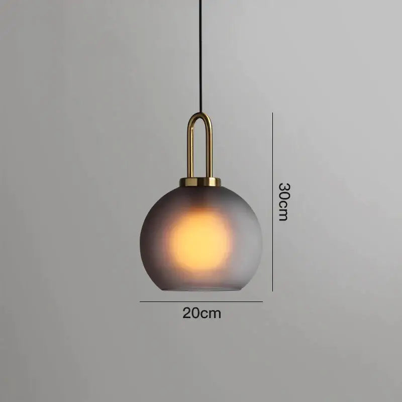 A sleek modern gray glass ball pendant light with frosted shade and brass accents ideal for dining room decorbites