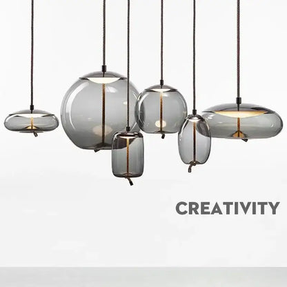 Set of modern gray glass knot pendant chandelier lights with translucent shades and black cords for dining room use