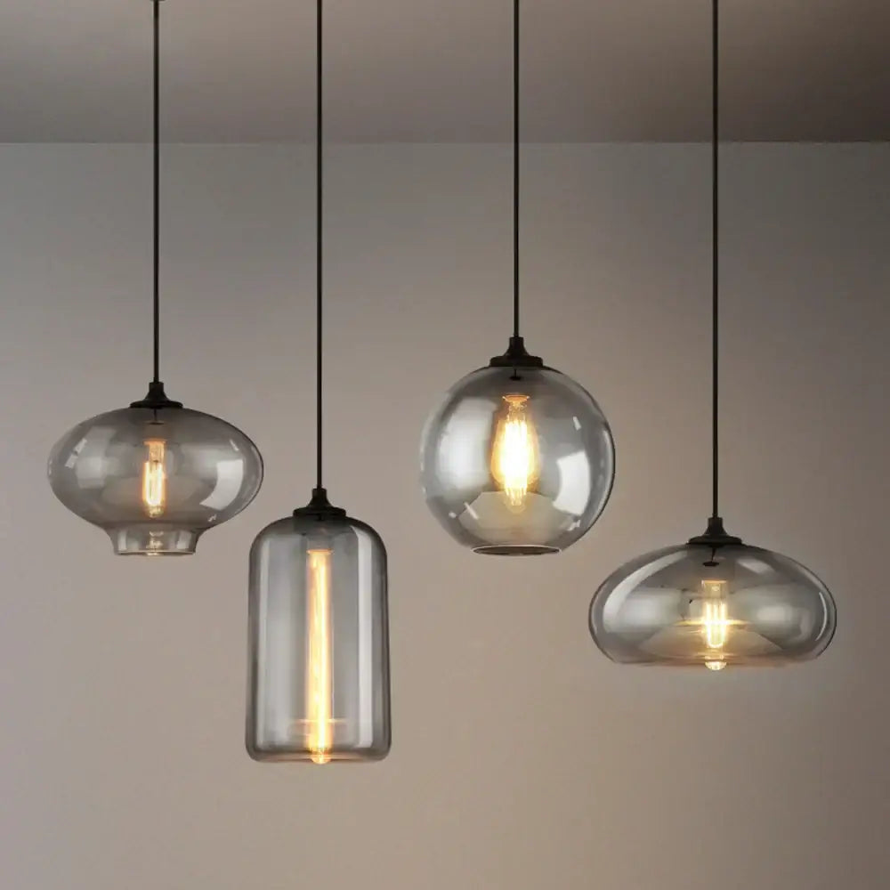 Set of four modern gray glass pendant lights with warm filament bulbs and black cords for dining room lighting