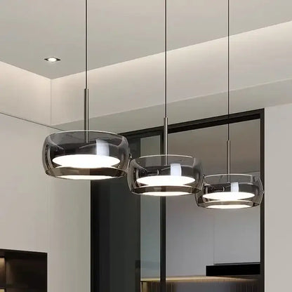 Three modern pendant lights with sleek gray glass and plated detailing designed for kitchen use