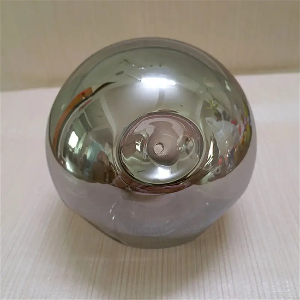Shiny chrome-finished spherical light bulb with reflective surface and central threaded base for gray glass shade replacement