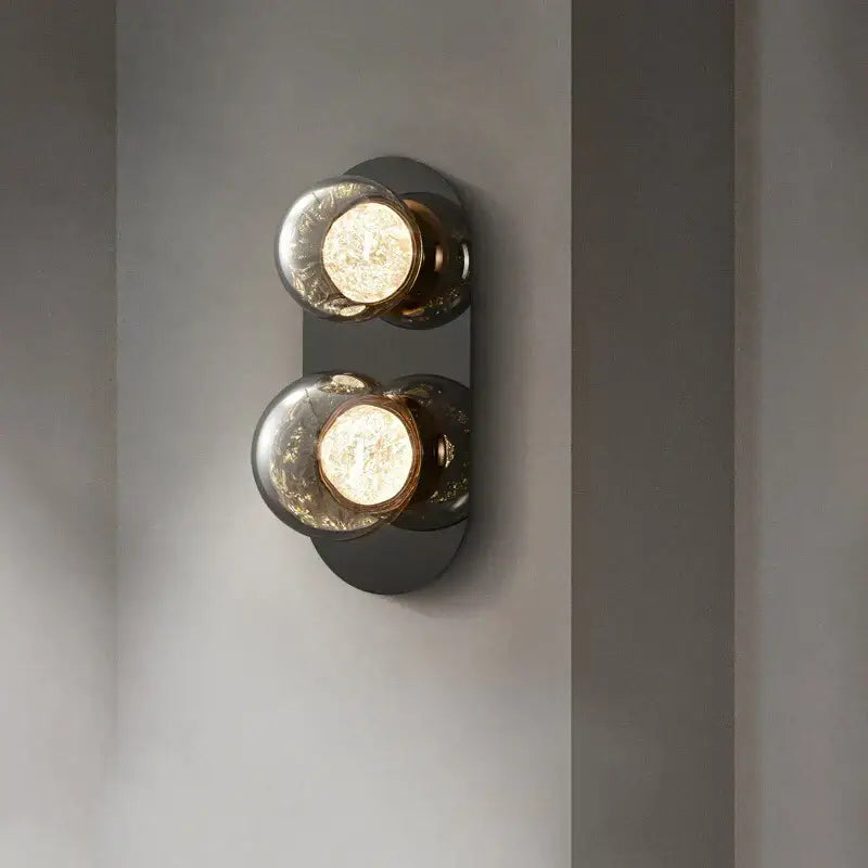 Modern gray glass wall lights with two crackled spherical bulbs in a matte black metal frame for living room use
