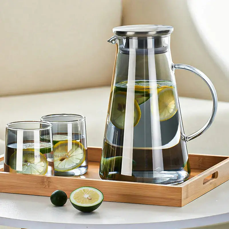 Modern gray glass water pitcher with stainless steel lid and handle filled with water and sliced lemons