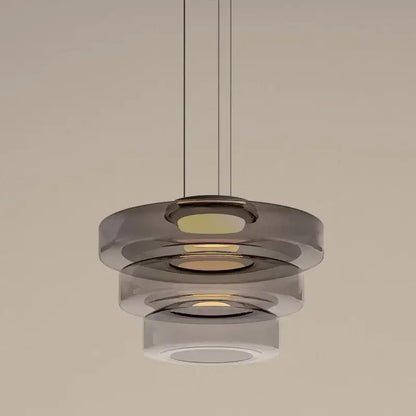 Modern gray and green tiered glass pendant light with translucent glass rings and warm glow for dining room