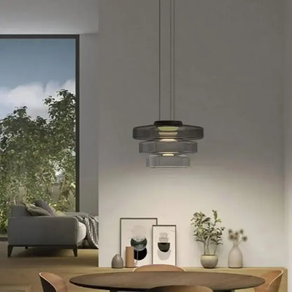 Modern gray and green tiered pendant light with translucent glass shades and black metal frame for dining room use