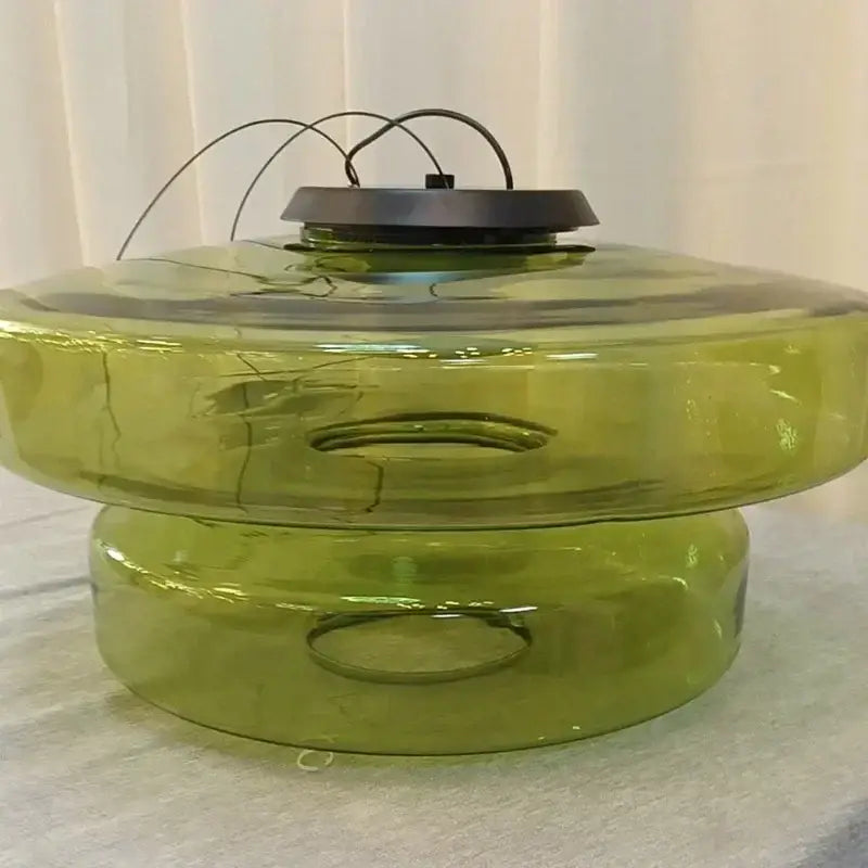 Modern gray and olive-green glass pendant light with black metal top and hanging wire for dining room lighting