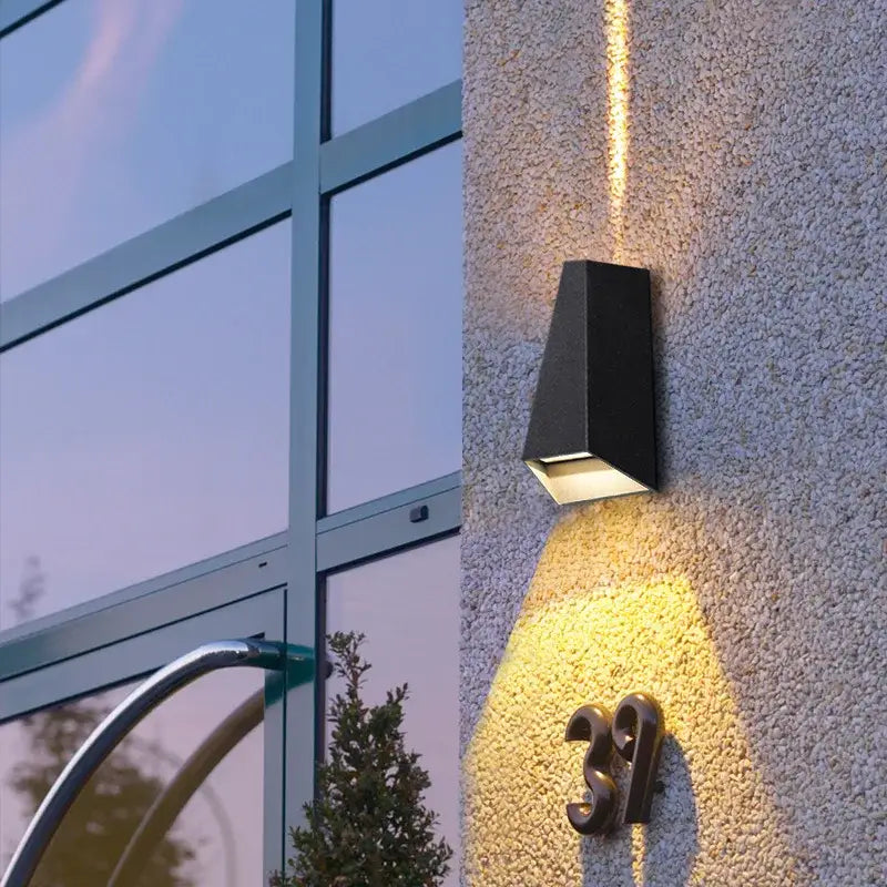 Modern gray led wall washer outdoor sconce with a black rectangular design emitting warm yellow illumination for garden use