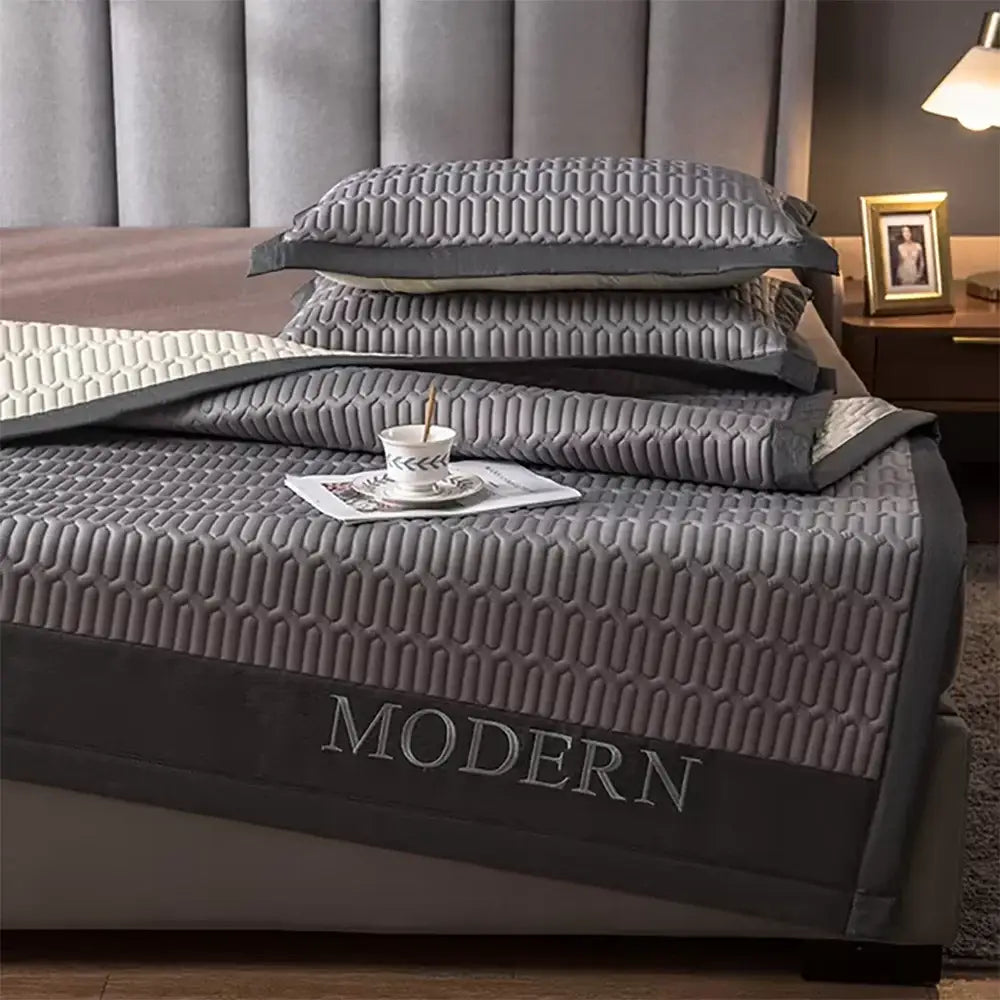 Modern gray quilted cooling latex bed mat featuring a subtle geometric pattern and modern embroidery along edge