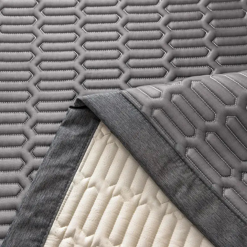 Modern gray quilted cooling latex bed mat with hexagonal stitching and contrasting cream-colored backing for bedroom use