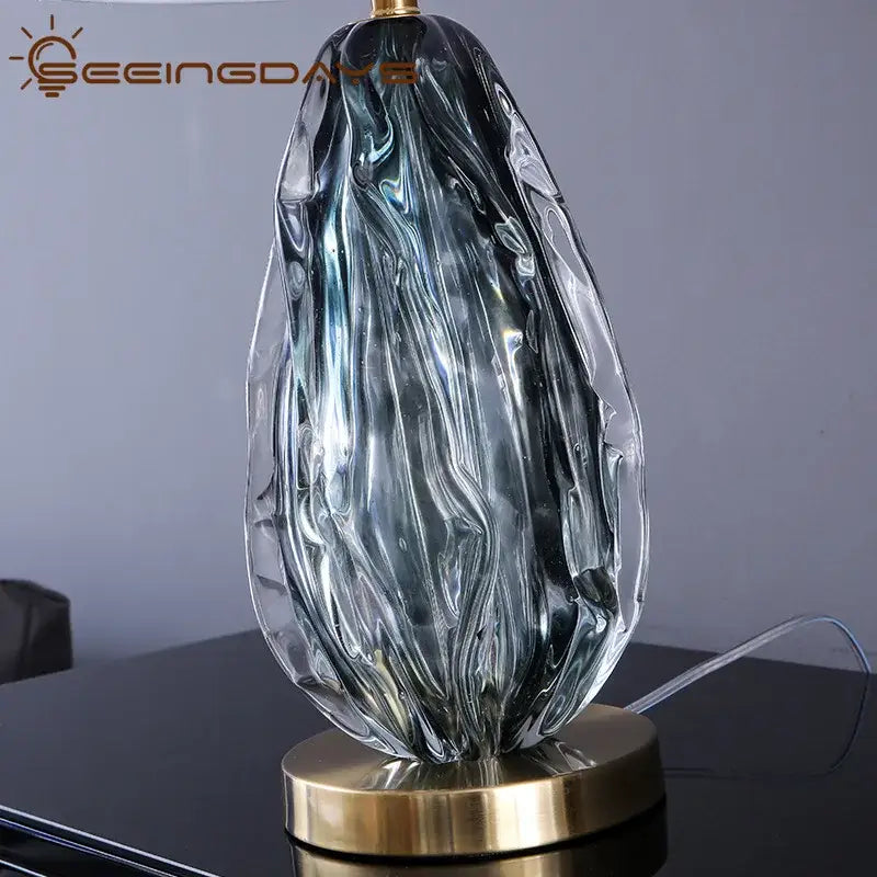 Modern gray swirl crystal table lamp featuring a sleek translucent blue glass form and gold-toned metal base decorbites crystal table lamp