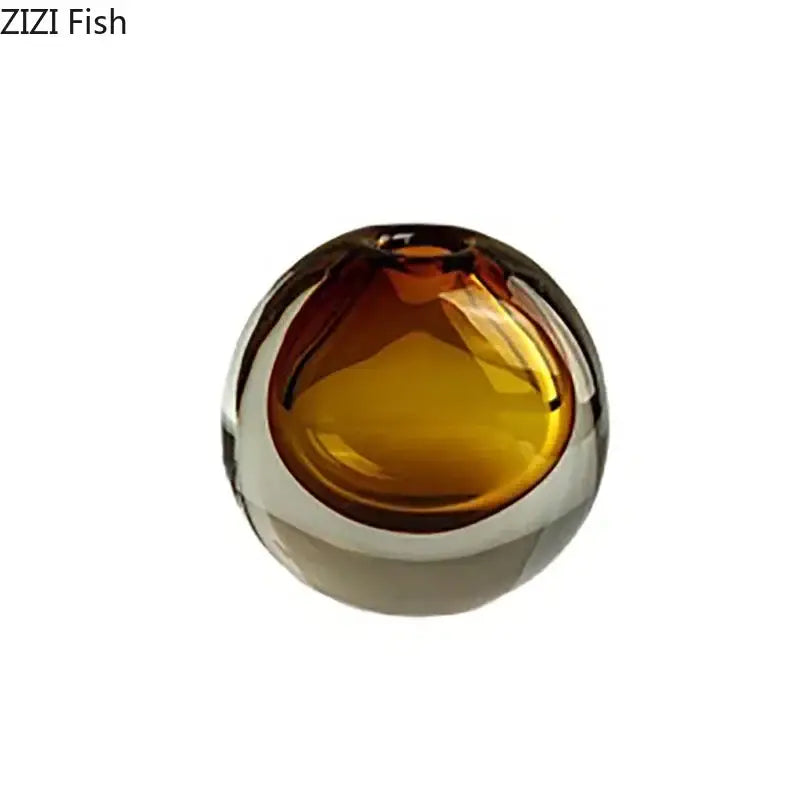 Amber-colored glass fish-shaped decorative bowl with glossy surface paired with modern gray teal glass vase and artificial flowers for home decor