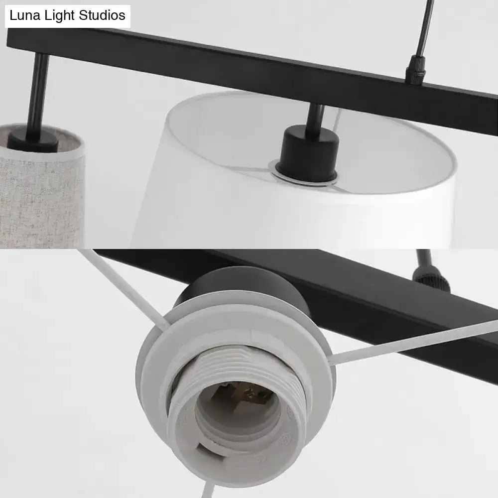 Black metal barrel hanging light fixture with five white fabric lamp shades and visible light bulb sockets