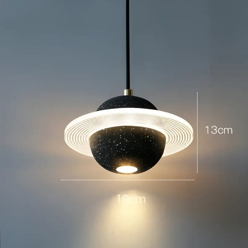 Black speckled decorbites cement planet pendant light with glowing white ring and gold hardware for modern bedroom decor