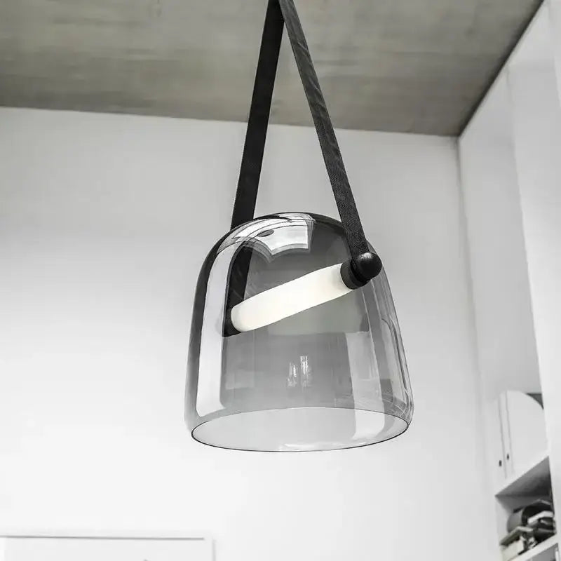 A modern gray and white decorbites glass chandelier with a sleek translucent glass pendant and black fabric strap