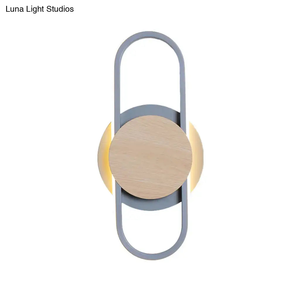 Modern gray and wood geometric led sconce with sleek metal frame and central wooden disc emitting white light