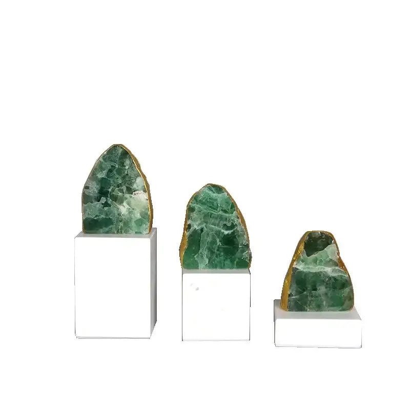 Three green aventurine geodes with gold-edged rims on white pedestals as modern green agate crystal stone bookends