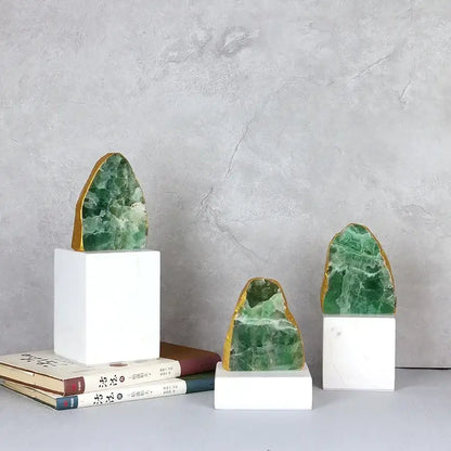 Three green agate crystal stone bookends with gold-edged surfaces on white marble bases for living room decor
