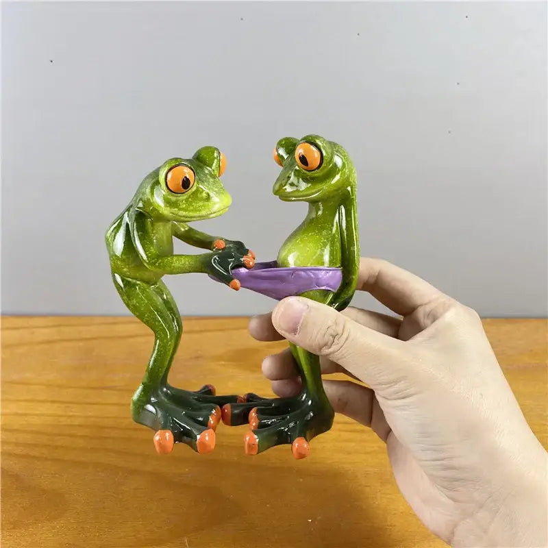 Modern green and orange leggy frog couple figurine holding a purple object perfect for living room decorbites decor